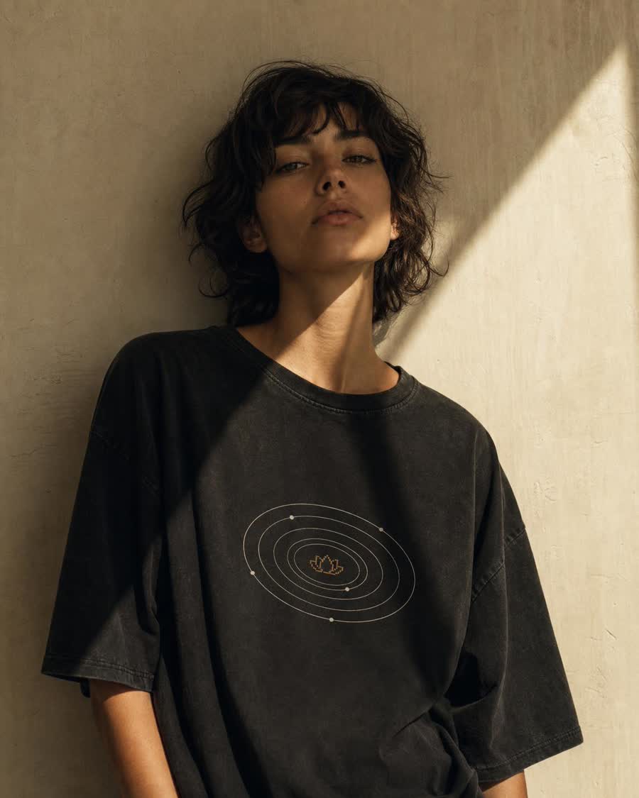 Washed-black tee with orbital rings around a pixel lotus
